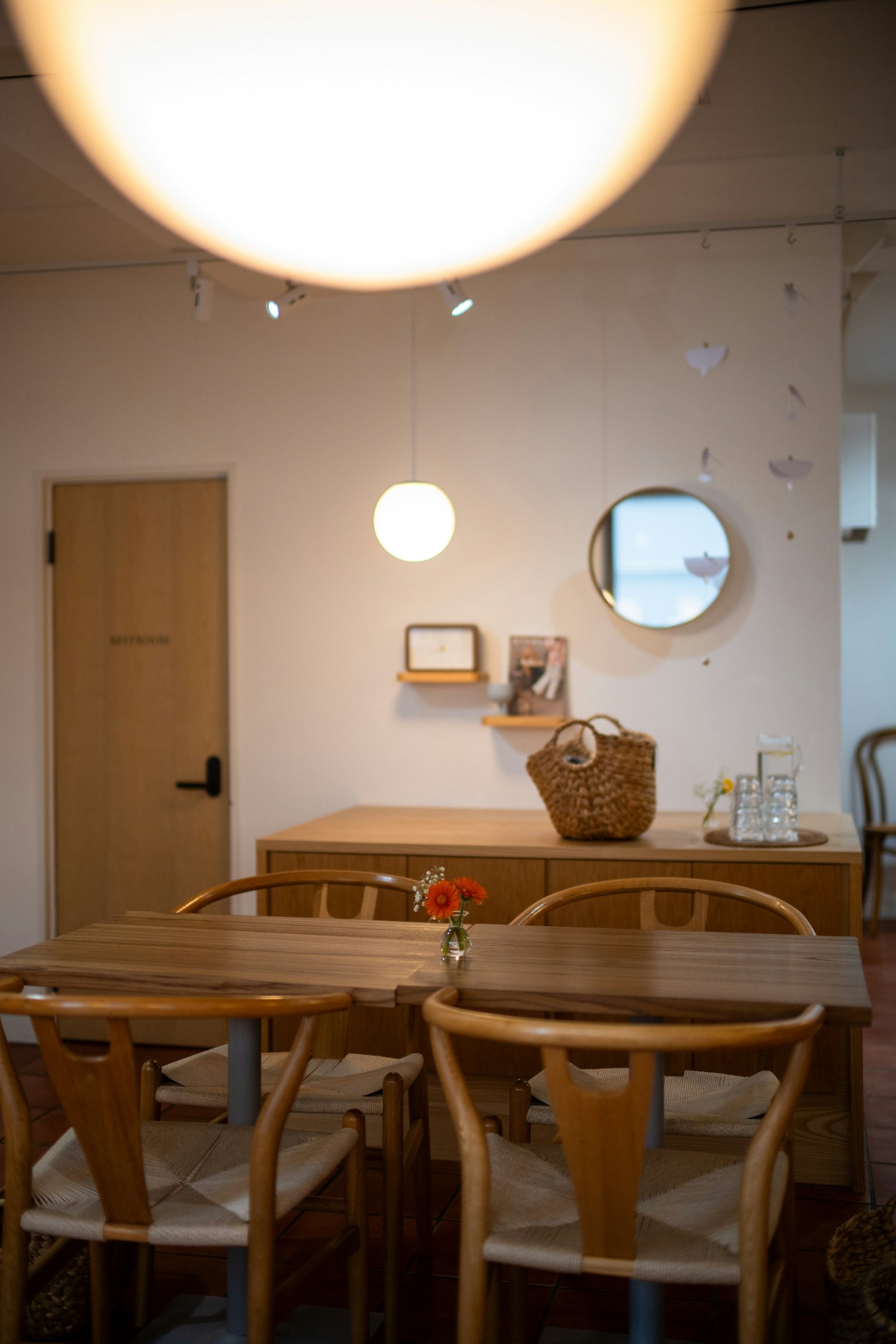 Warm daylight inside the Noir House dining room, plants and wood tables
