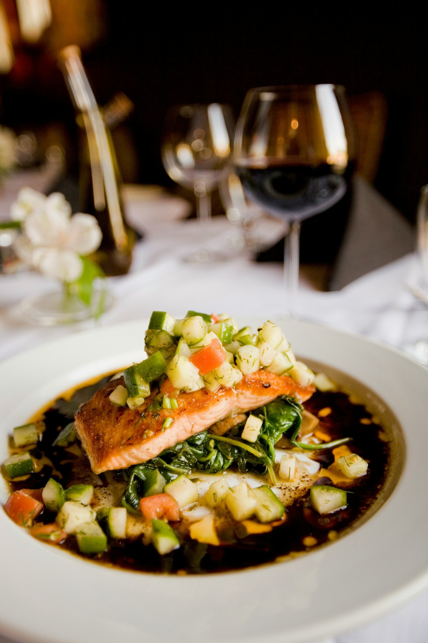 Salmon fillet plated with salsa and a glass of red wine at Noir House